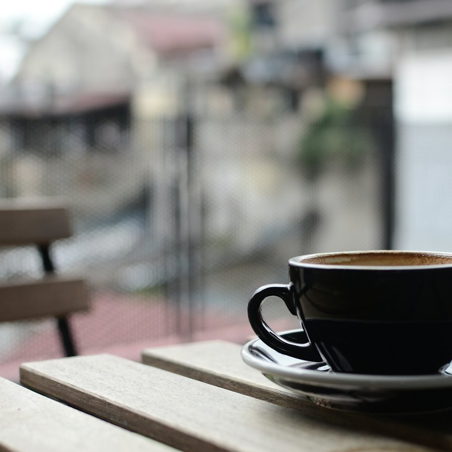 木のテーブルに置かれた黒いマグカップのコーヒー